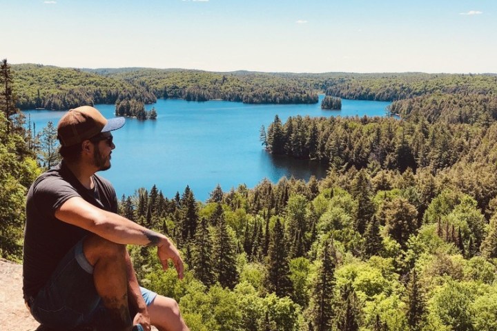 a man standing next to a river with Blue Lake in the background