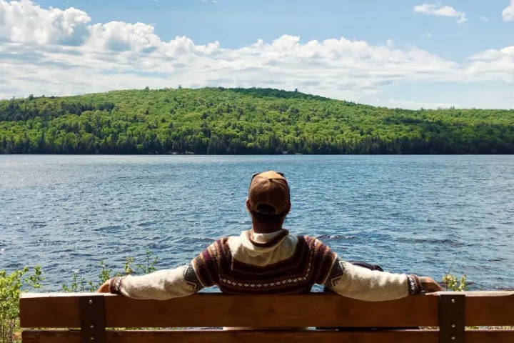 a man sitting on a bench in front of a body of water