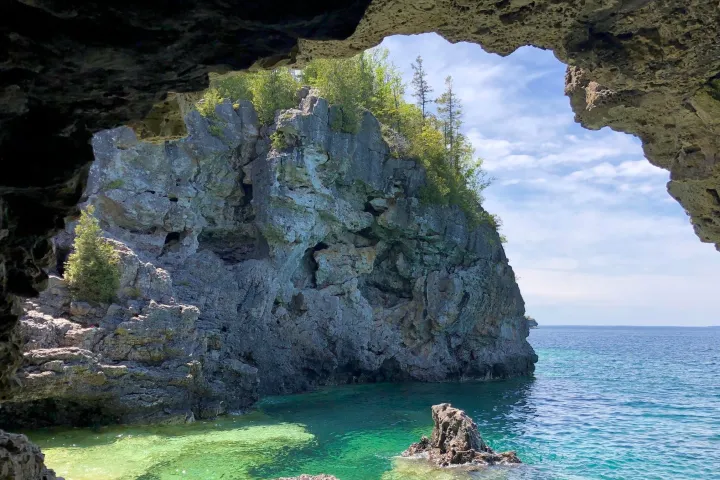a rocky cliff with water and a mountain in the background
