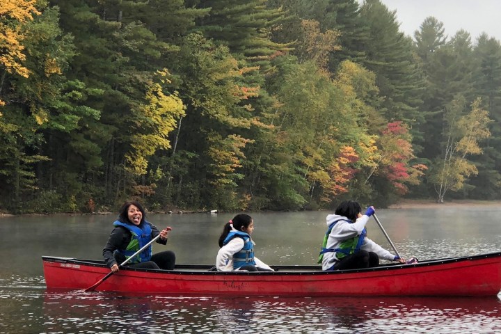 a man riding on the back of a boat next to a lake