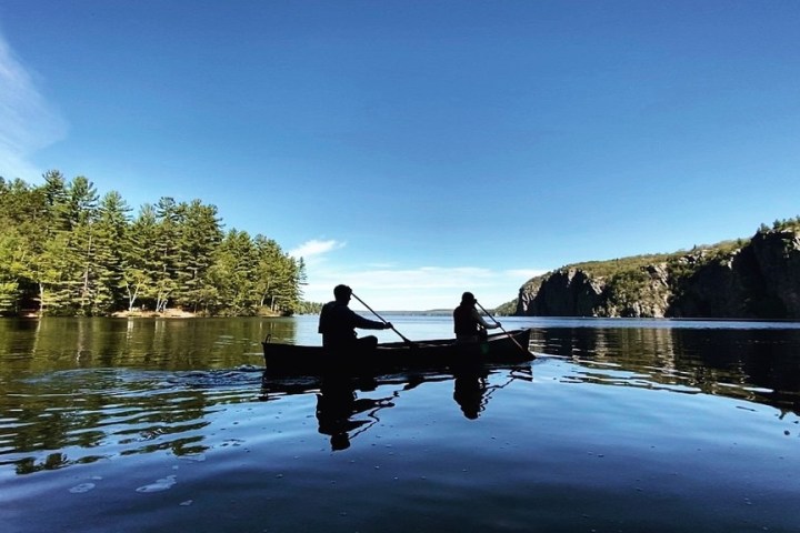 a person riding on the back of a boat next to a lake