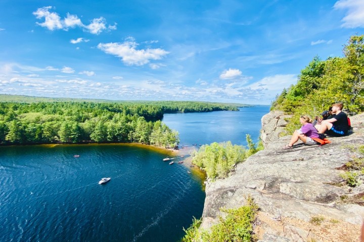 a group of people sitting next to a body of water