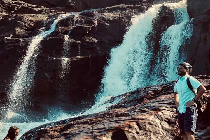 a man standing next to a waterfall