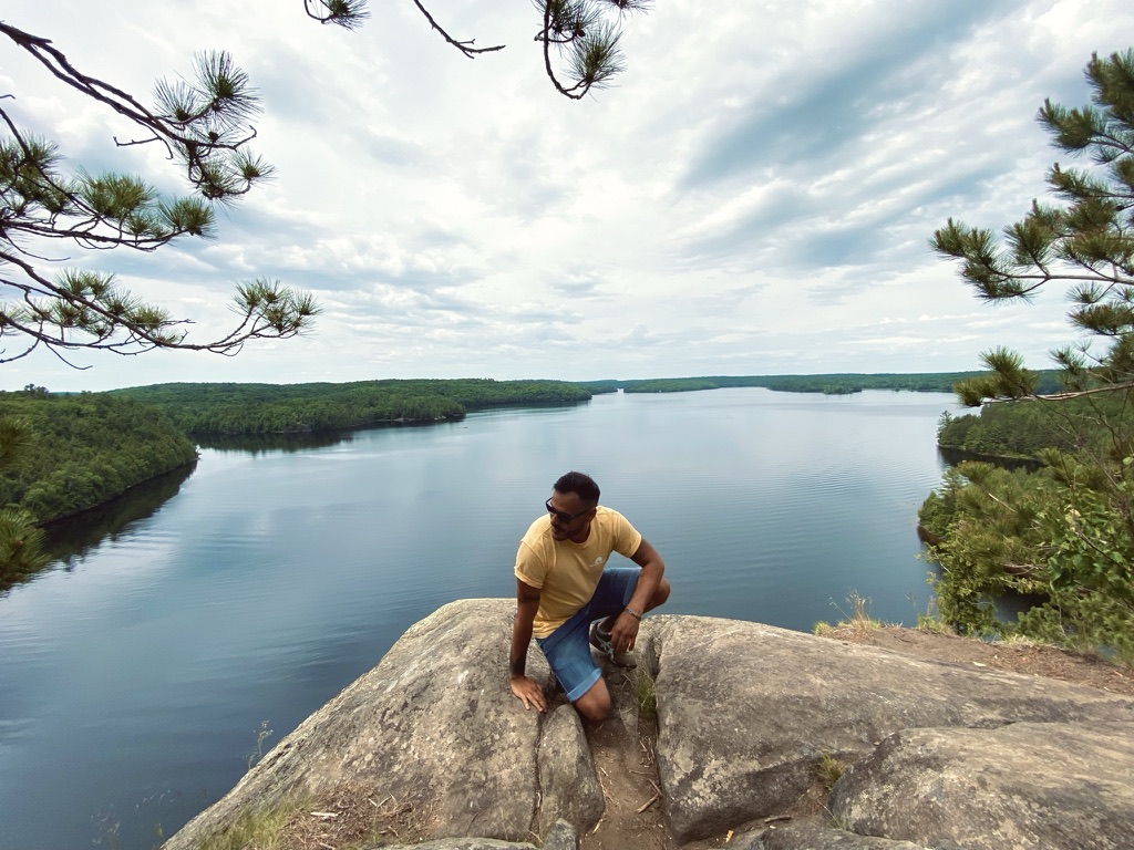 a man sitting on a rock next to a body of water