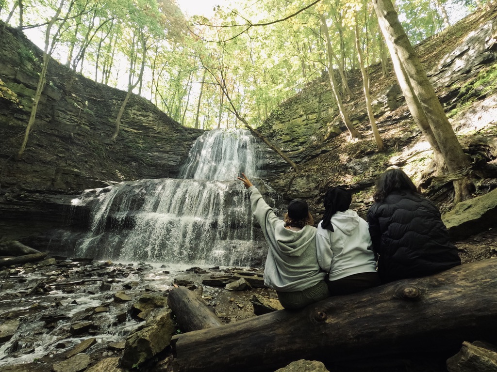 a person sitting on a rock next to a waterfall