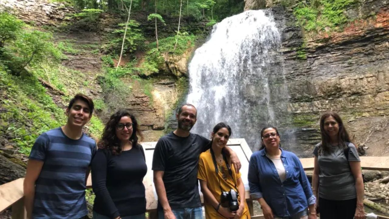 Large Tiffany falls cascading down layered rock cliffs in a lush wooded area
