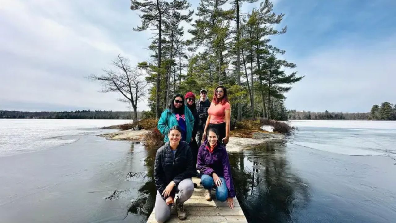 People in a guided tour by Toronto EcoAdventures standing on a narrow wooden dock between partially frozen lakes