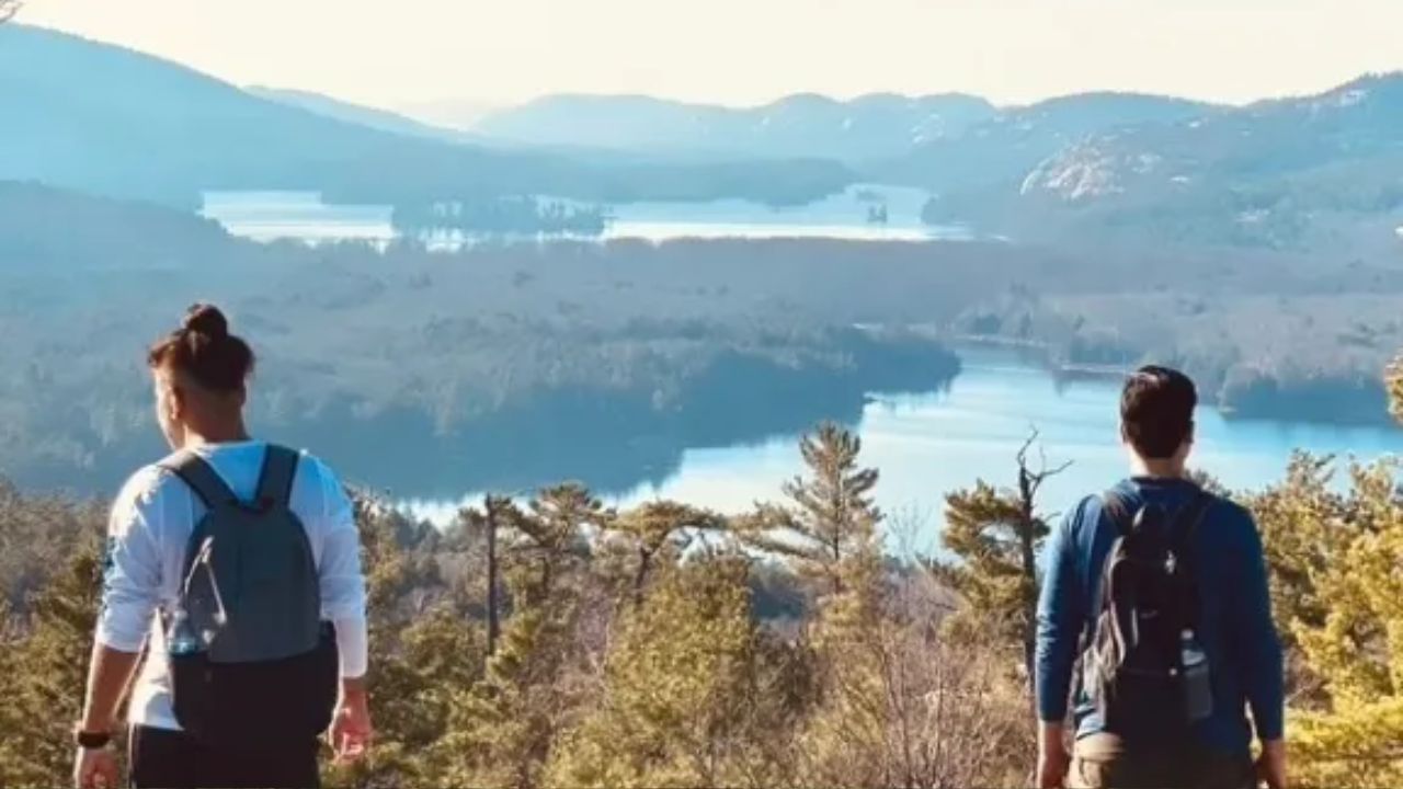 Two hikers with backpacks standing on a mountain viewpoint