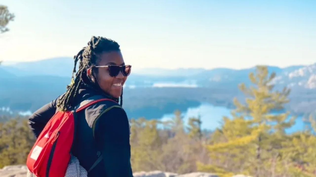 Person hiking with red backpack overlooking mountain lake viewpoint at Muskoka