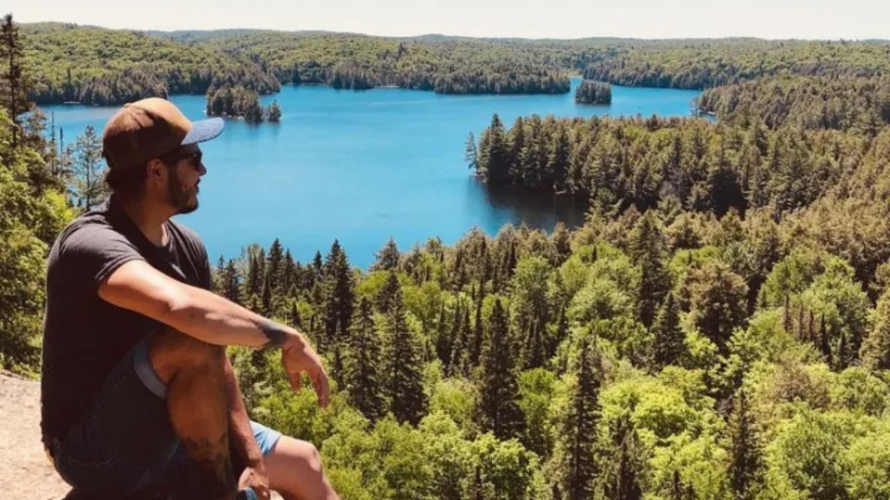 Man sitting on a cliff enjoying a panoramic view of Algonquin Park. 