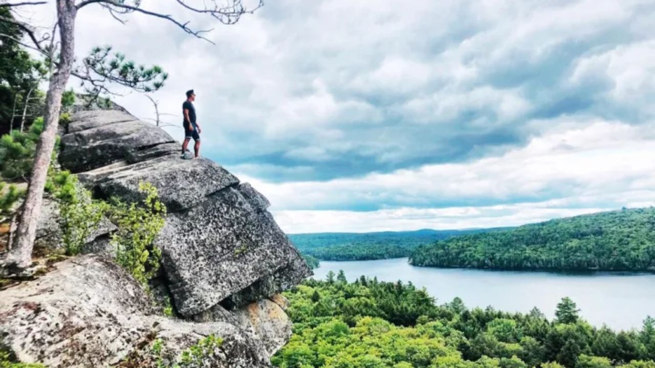 Hiker standing on a rocky cliff overlooking Algonquin Park.