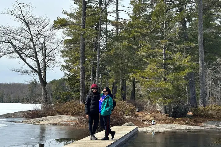 Friends posing on a wooden dock beside a peaceful lake in Muskoka