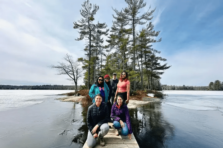 Group of hikers on small island surrounded by frozen a lake in Muskoka