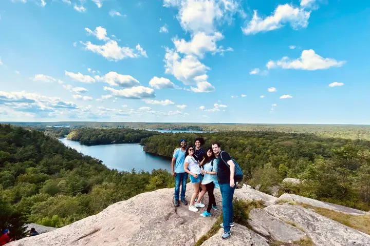 Group of hikers standing on a rocky lookout with panoramic lake views in Rock Dunder