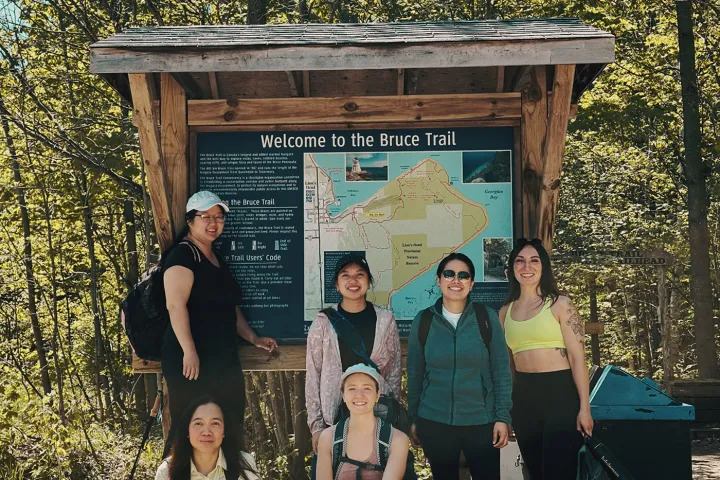Hikers posing beside a Bruce Trail information board before their adventure.