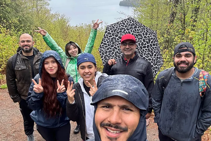 Hiking group smiling on trail with lake view in background