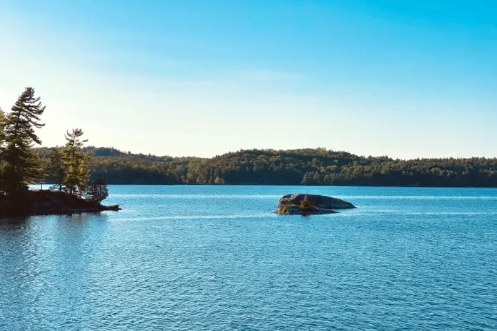 Peaceful lake with small rocky islands and pine trees in the Rock Dunder cottage country
