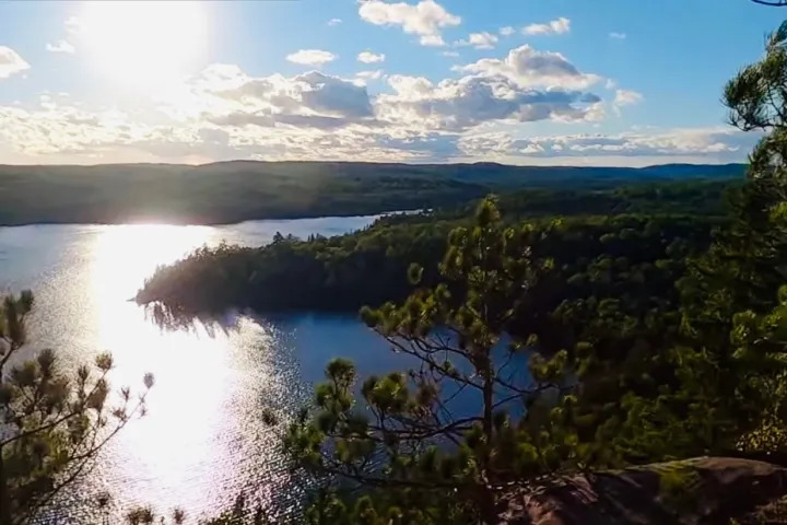 Sunlit wilderness landscape with forested islands and calm blue water at Algonquin Park