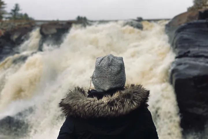 Traveller watching a powerful waterfall surrounded by rocky cliffs in Muskoka
