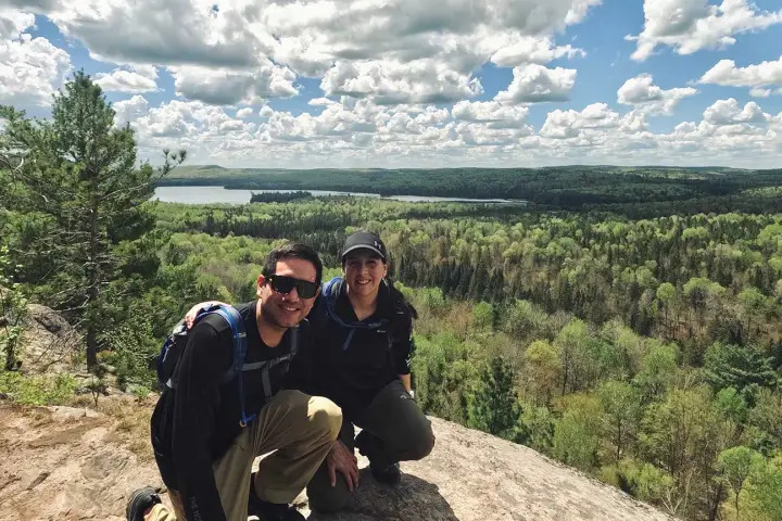 Hikers posing at a scenic Algonquin Park lookout with sweeping views of forests, lakes, and rugged wilderness.