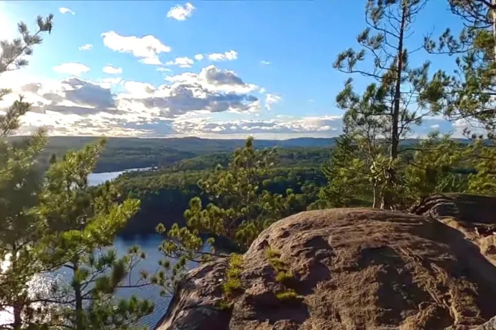 Scenic lookout with rocky cliffs, pine trees, and sweeping views of Algonquin wilderness.