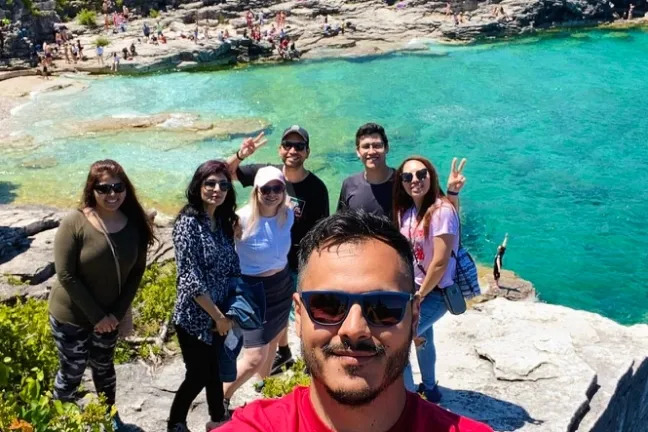 Travellers posing above the famous Grotto, surrounded by vibrant blue water and rocky coastal landscapes