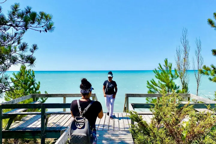 Visitors standing on a wooden observation deck overlooking the turquoise waters of Lake Huron.