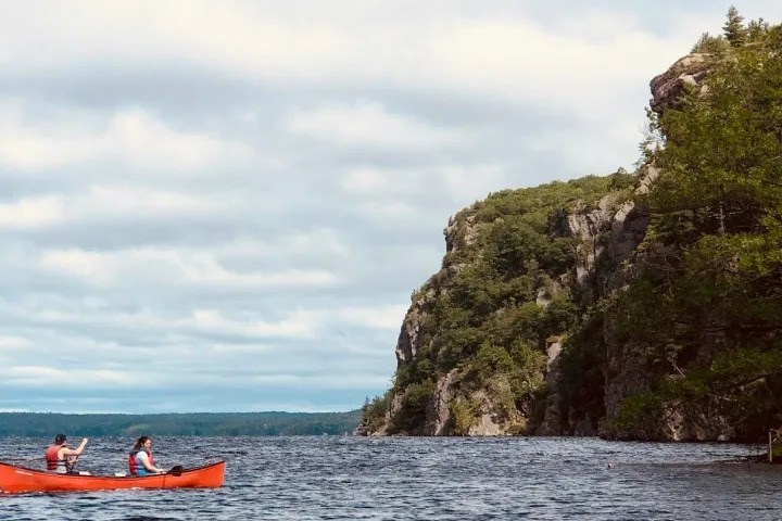 Canoe exploring the scenic shoreline and rugged cliffs of Bon Echo Provincial Park on Mazinaw Lake.