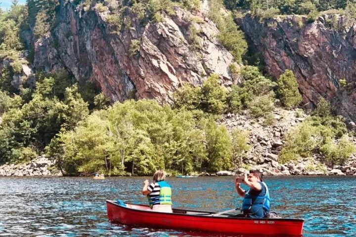 Canoeists exploring the clear waters and rugged cliffs of Mazinaw Lake in Bon Echo Provincial Park.
