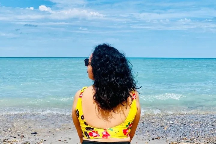 Visitor enjoying the scenic shoreline and turquoise waters at Grand Bend Beach in Ontario.