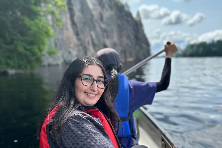 Visitors paddling a canoe on Mazinaw Lake beneath the towering cliffs of Bon Echo Provincial Park.