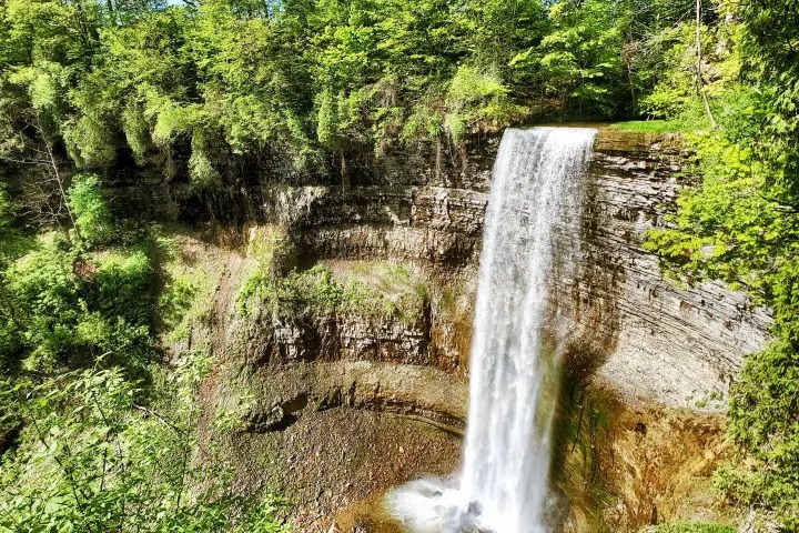 Beautiful tiered waterfall surrounded by forest along a scenic hiking trail.