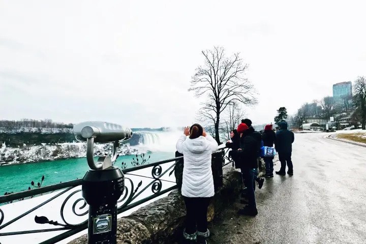 Tourists viewing Niagara Falls from a scenic observation point in winter.