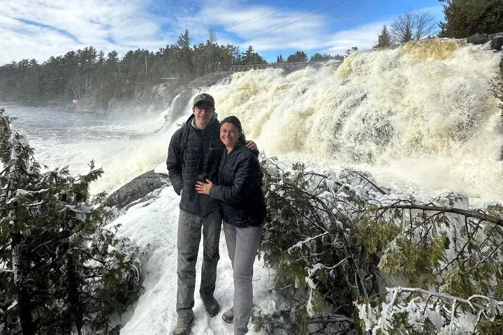 Visitors enjoying a spectacular winter waterfall surrounded by snow-covered scenery.
