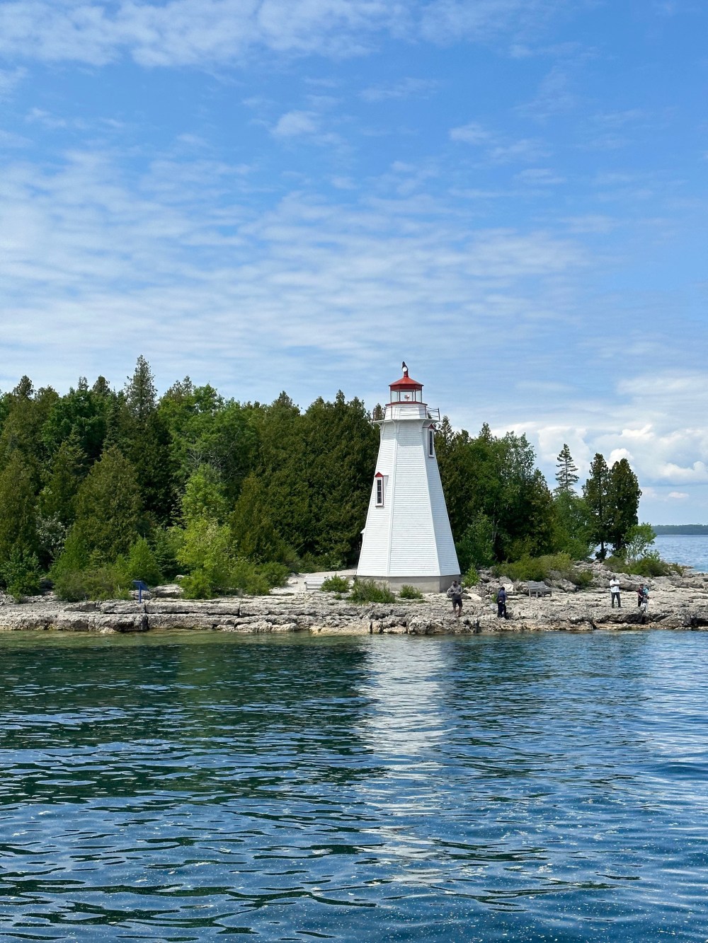 Visitors enjoying panoramic views of brilliant turquoise water, limestone cliffs, and forested shoreline near Tobermory, Ontario