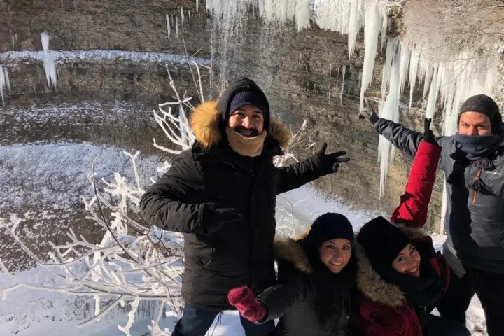 Visitors exploring a frozen waterfall with ice formations during a winter tour.