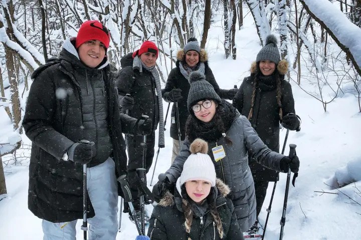 Snowshoers bundled up in heavy jackets posing on a snowy trail.